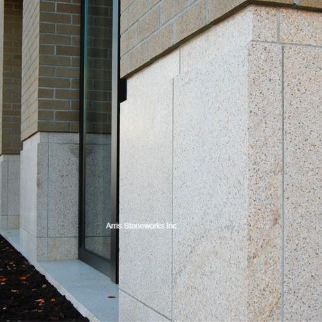 Close-up detail of a large-format Sorrel Granite wall panel with a smooth honed finish at People's Bank.