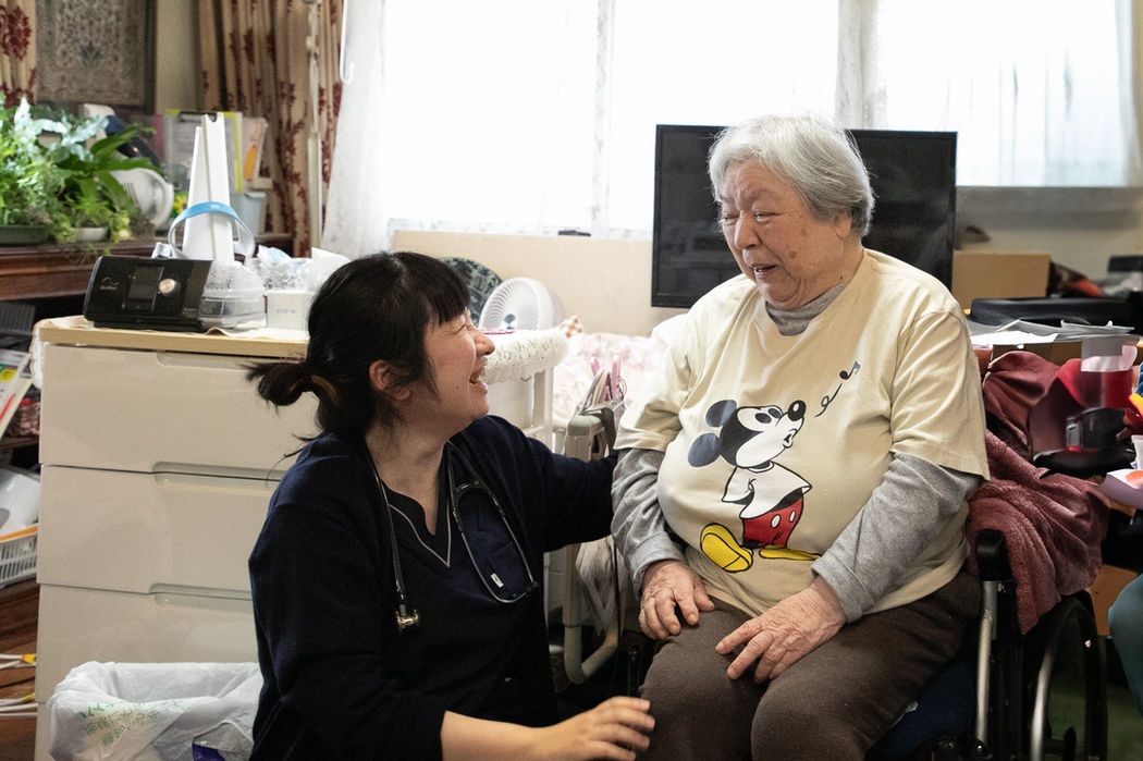 医師、看護師と高齢女性が笑顔で話す様子。