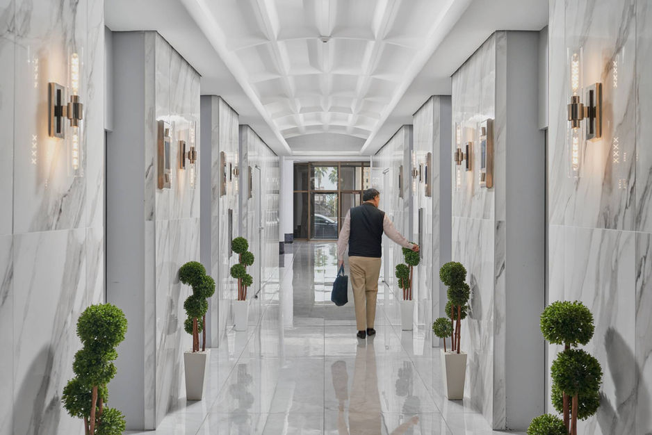 Luxurious corridor at Broadway Tower in Corpus Christi, TX featuring marble walls, topiary plants, and upscale architectural finishes.