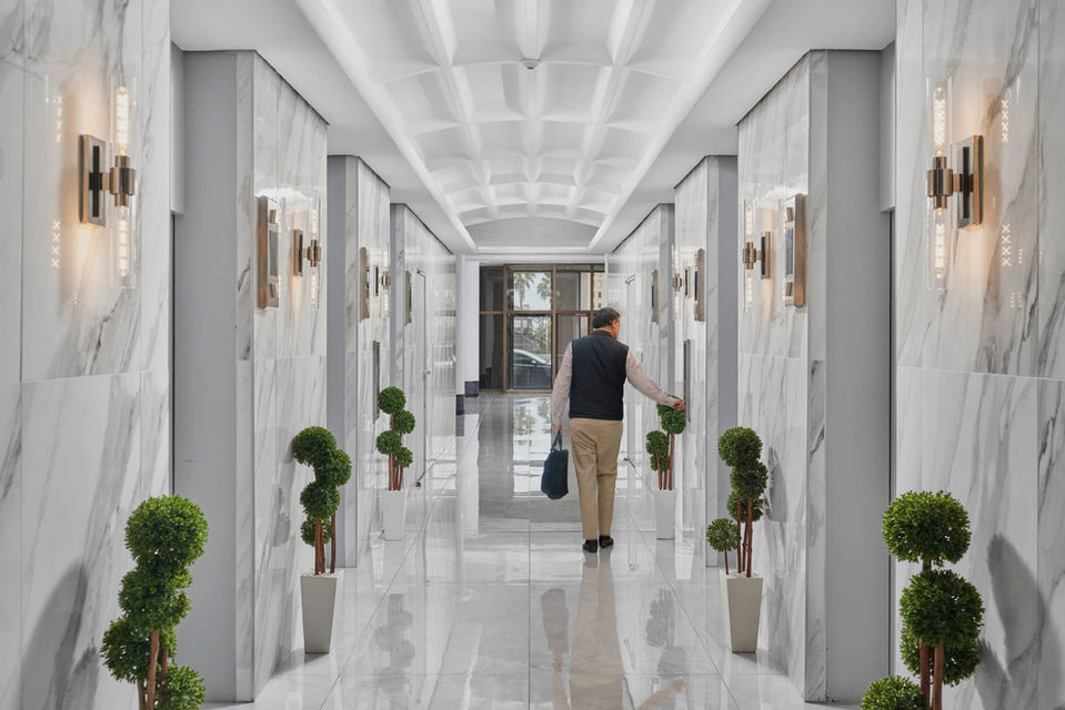 Luxurious corridor at Broadway Tower in Corpus Christi, TX featuring marble walls, topiary plants, and upscale architectural finishes.