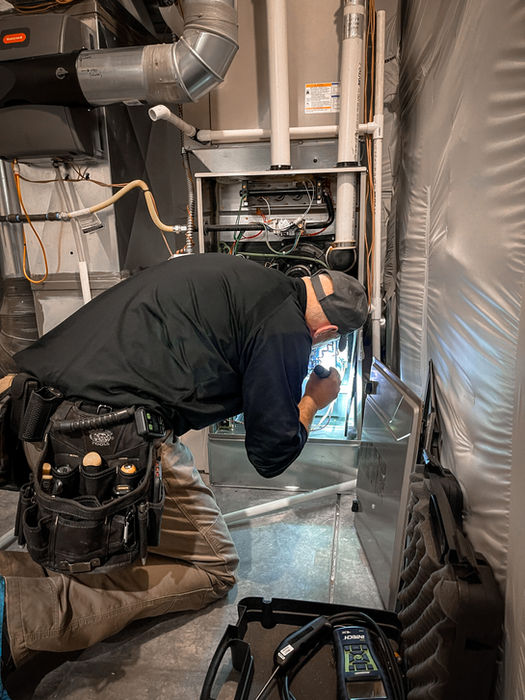 Technician inspecting an HVAC furnace with a flashlight