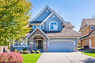 Modern blue two-story house with stone entryway and lawn.