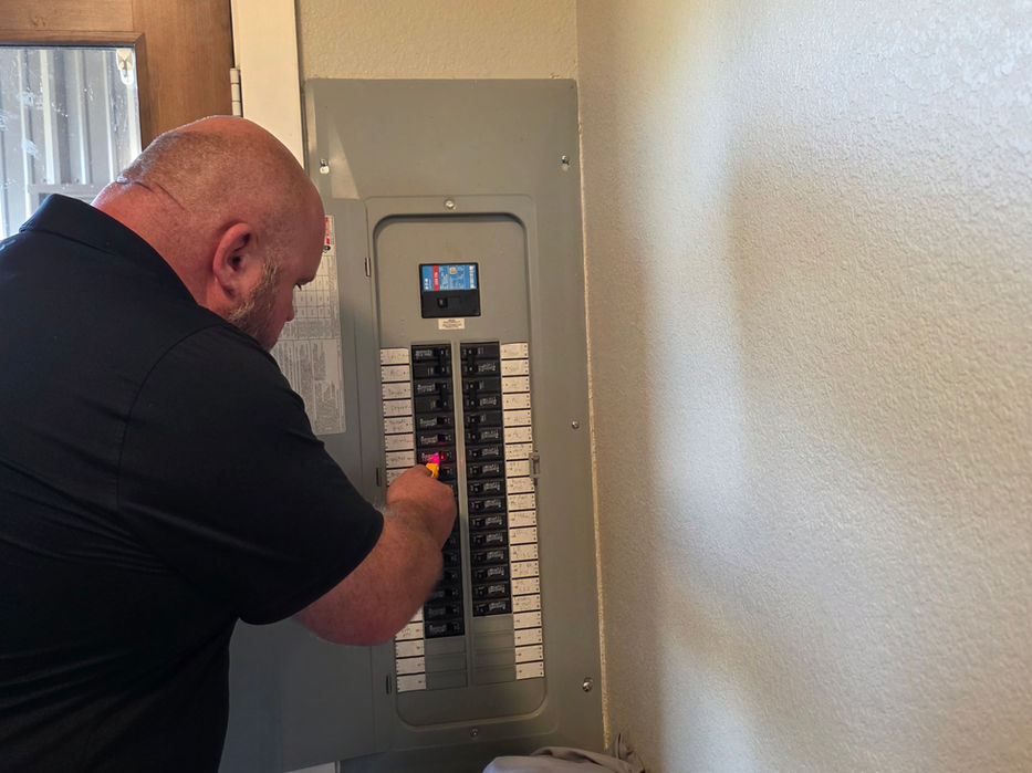 Electrician inspecting a residential circuit breaker panel.