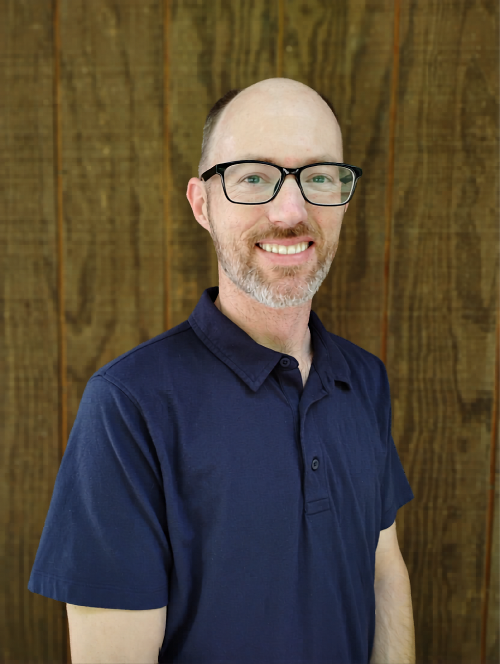 Smiling man with glasses in a blue polo shirt