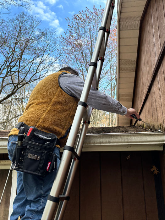 Professional on ladder working on house gutter