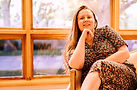 Woman in floral dress sitting by a window