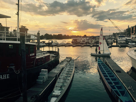 Boats docked in a harbor at sunset with dramatic sky