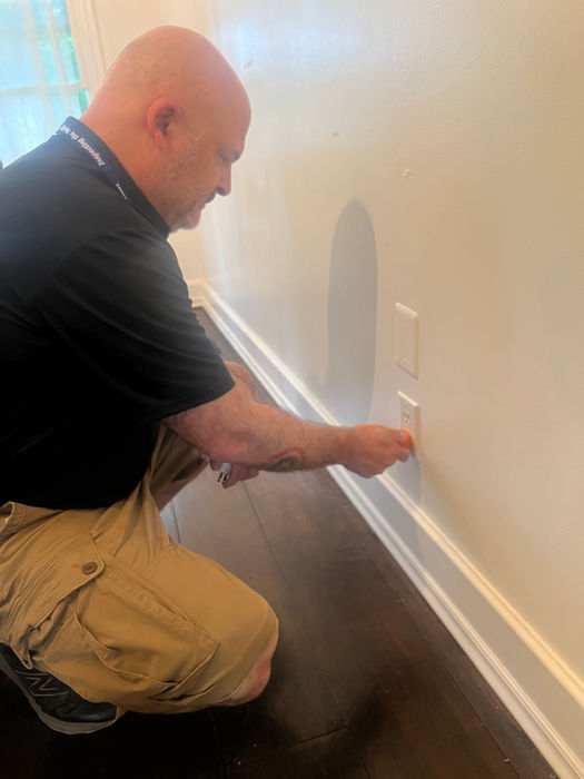 Technician inspecting a wall electrical outlet