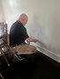 Technician installing an electrical outlet on a white wall