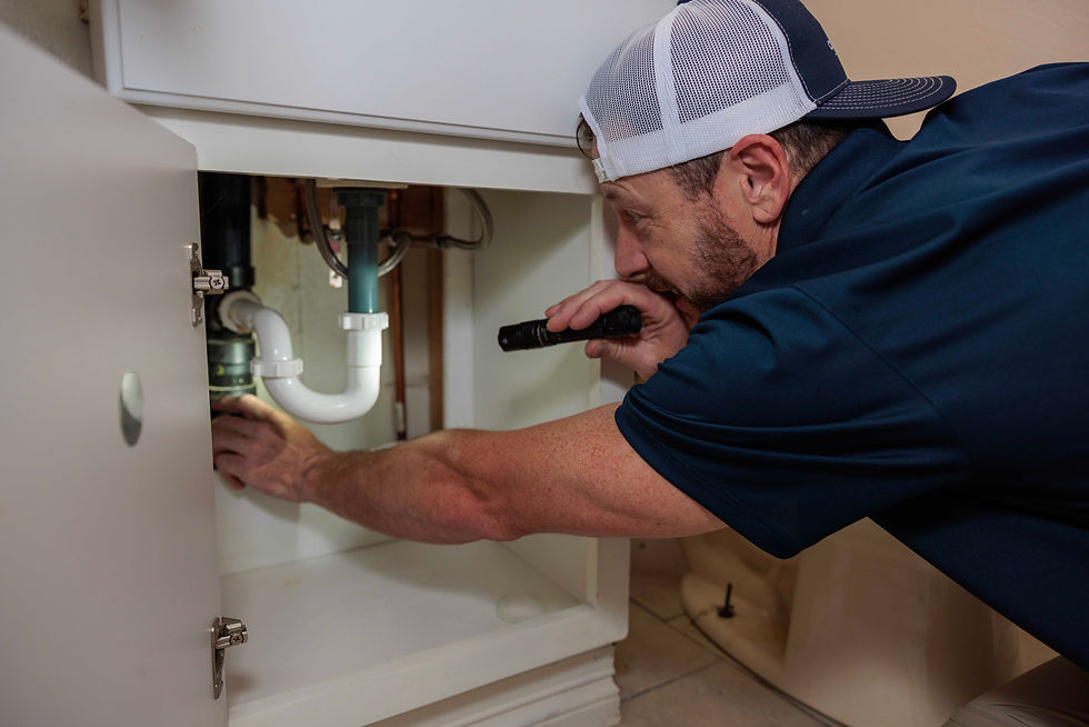 Plumber inspecting sink pipes with a flashlight