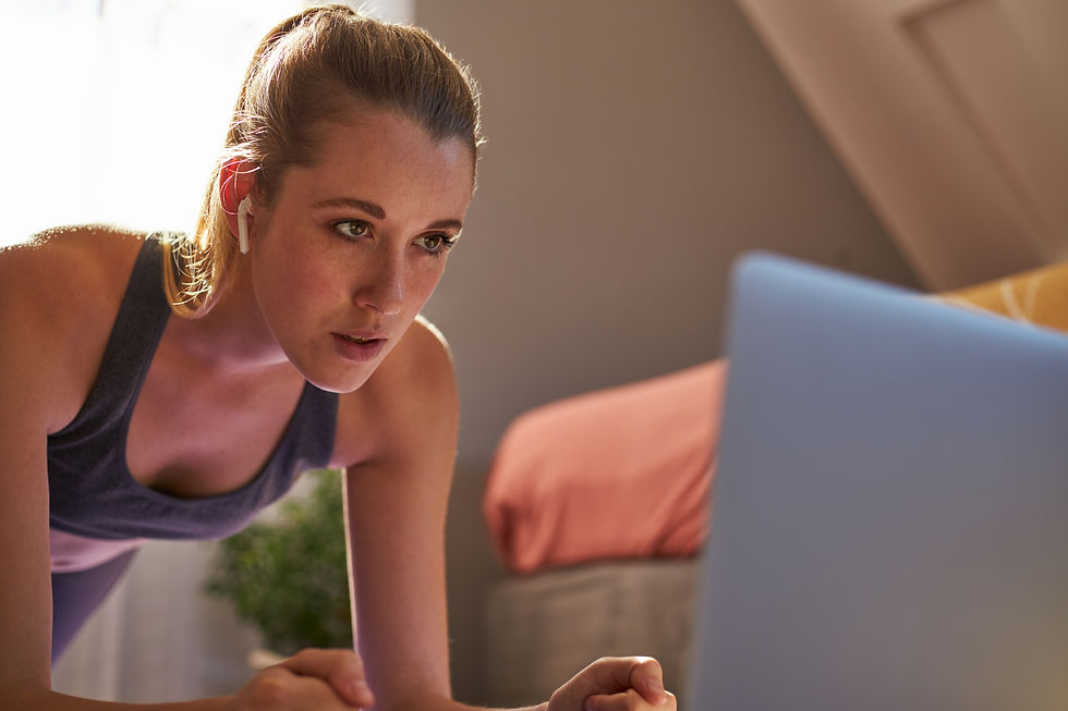 Woman doing plank exercise while looking at a laptop