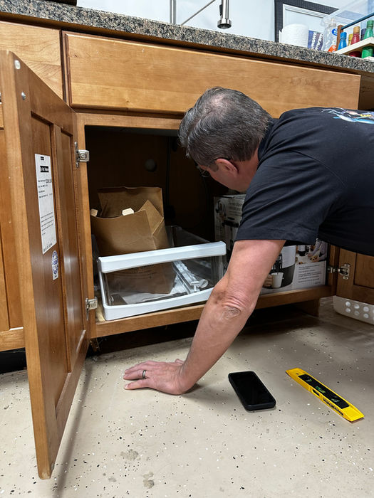 Man looking into an open kitchen cabinet