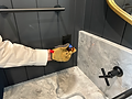 Gloved hand testing electrical outlet in a bathroom