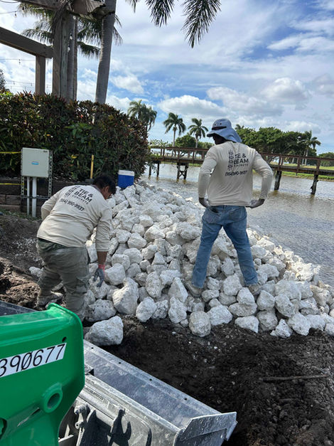 Workers moving white rocks along a waterfront