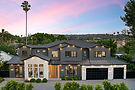 Modern two-story grey home at sunset with palm trees.