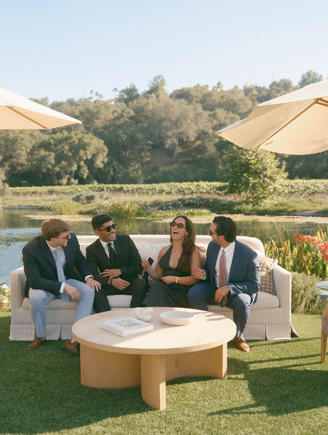 Wedding guests relaxing on a chic outdoor lounge setup with vineyard and lake views at Monserate Winery during cocktail hour.