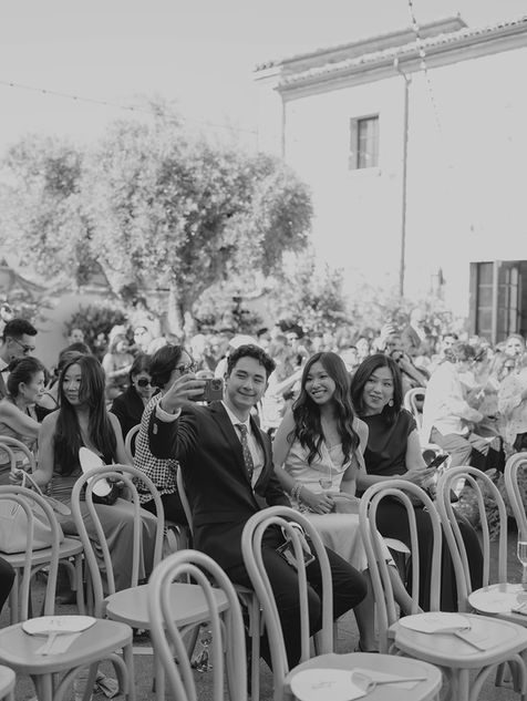 Wedding guests smiling and taking photos before the ceremony in Monserate Winery’s courtyard surrounded by Tuscan-style architecture.
