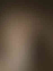 Golden hour portrait of the couple in soft light, standing against pleated drapes with the bride holding her bouquet.