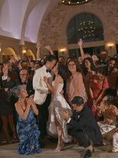 Bride, groom, and guests dancing and celebrating together during the evening reception inside Monserate Winery.