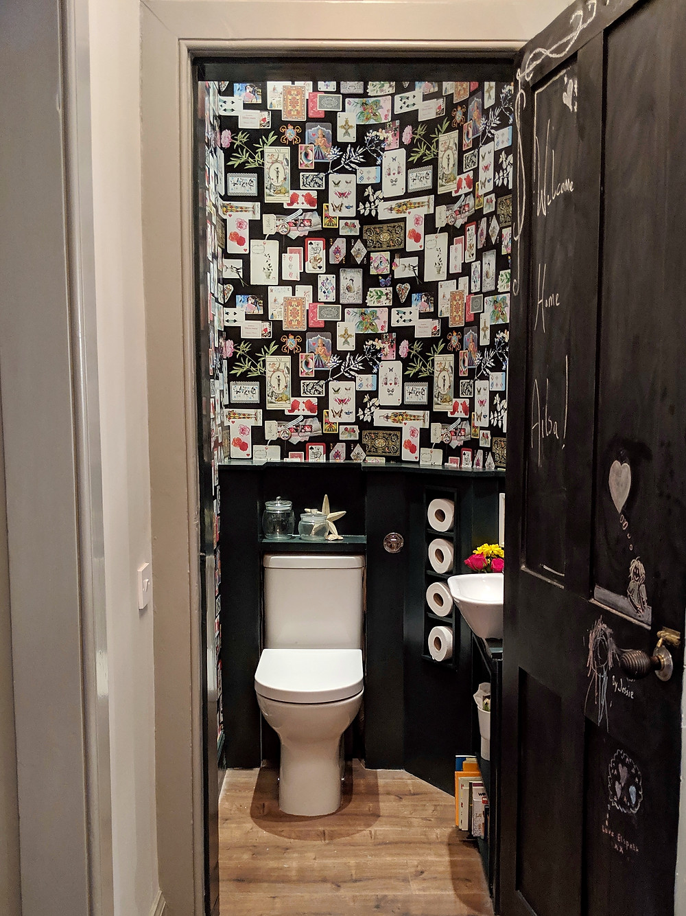 Blackboard door in wallpapered toilet.