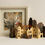 Thumbnail: Small paper townscape sculpture in front of framed tree artwork.