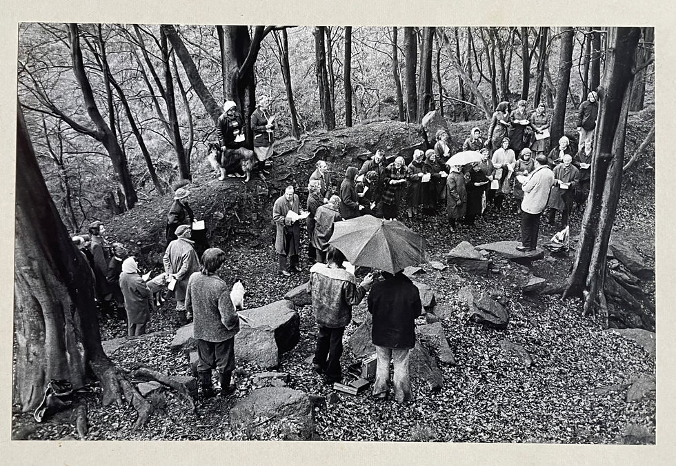Monochrome photograph of an outdoor congregation and preacher in winter woodland.