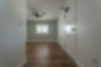 Empty apartment room with light green walls and wood floor