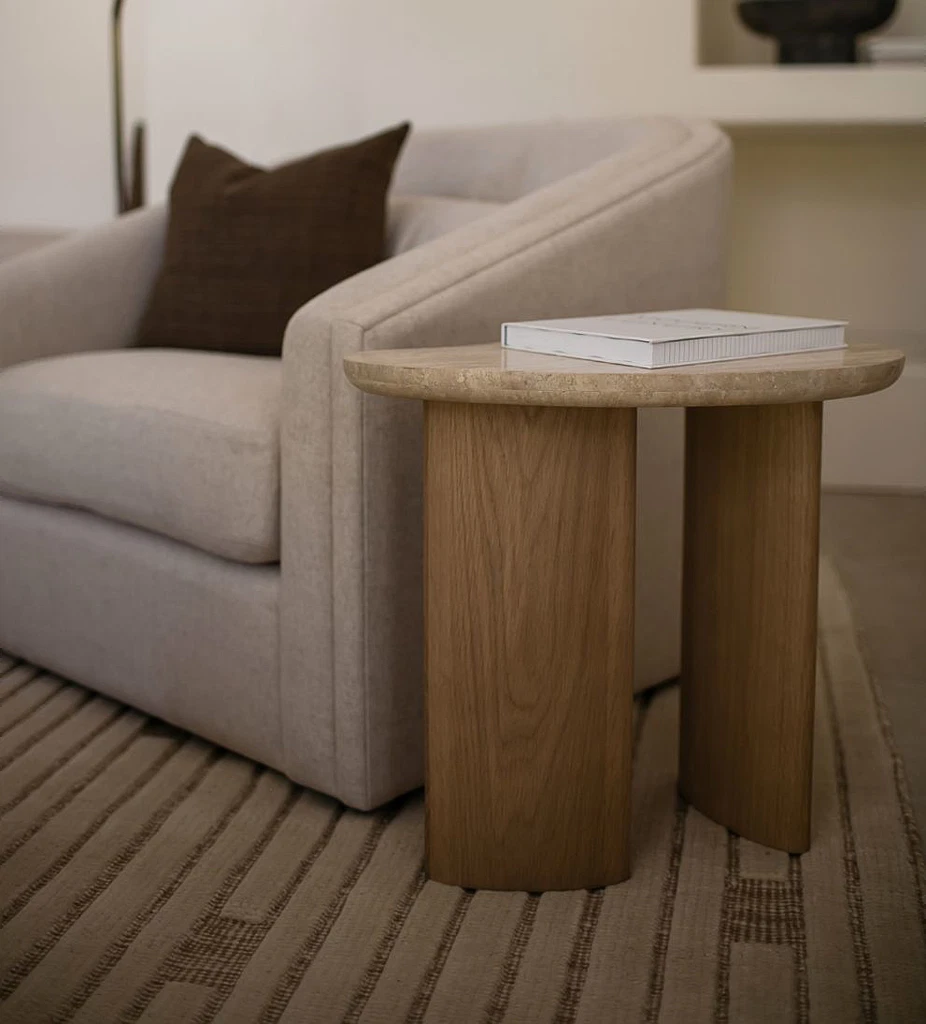 Side table with soft oval travertine top and dual oak wood column legs