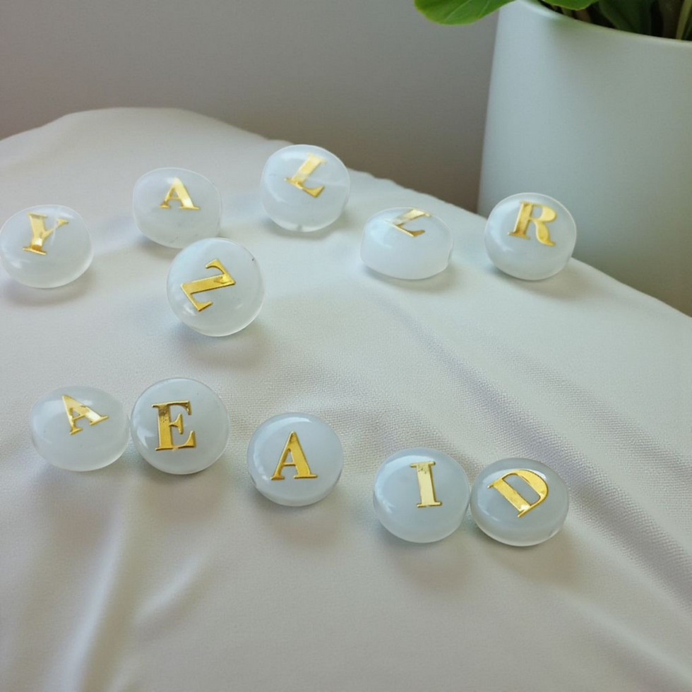 Perlmuttbuchstaben-Perlen: Goldene Buchstaben auf milchigem Hintergrund