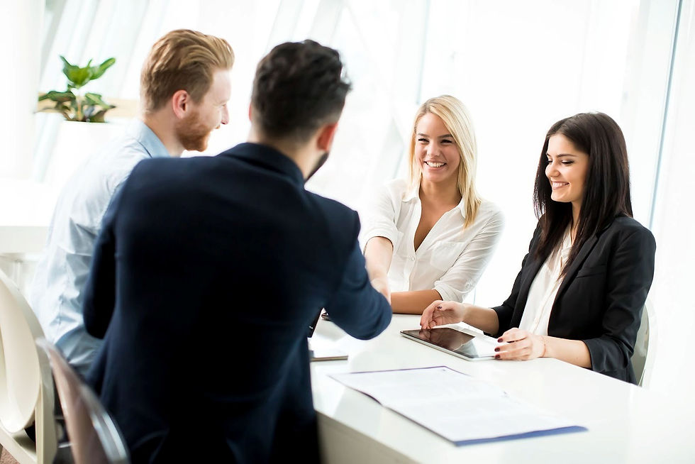 An insurance agent shakes hands with a client after a successful coverage presentation as their colleagues look on.