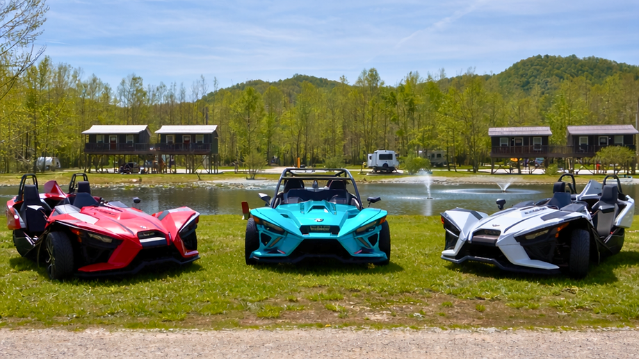 Polaris Slingshots parked in front of cabins and lake at Sheltowee RV Park near Cave Run Lake