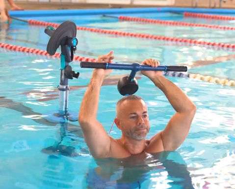 Man performing upper body exercises in an indoor pool.