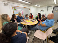 קבוצת אנשים יושבים סביב שולחן, דנים על משהו, עם הסיפור שלנו אודות מרכז פסג