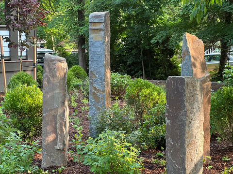 Tall stone pillars amidst green garden foliage