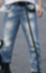 Man wearing faded straight leg jeans with black strip design with gold rings