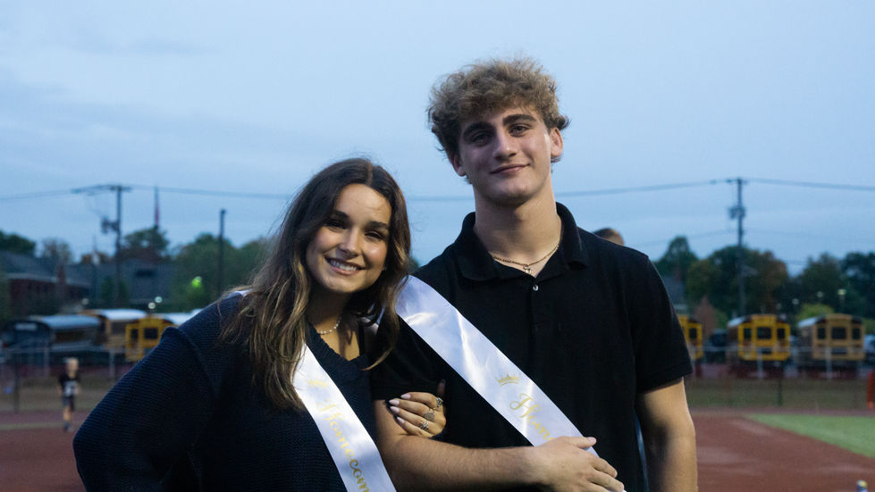 couple wearing homecoming sashes linking arms