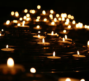 Image of many lit candles within a dark room