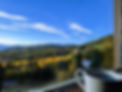 Image looking out of a window overlooking wooded mountains with a coffee cup on the window sill