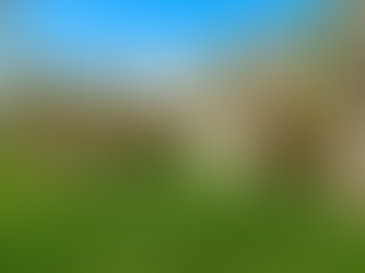 Exterior view of a light-green, single-story home in Canadensis, PA with tan trim, a small covered entry, and an attached two-car garage with wooden doors, set on a green lawn with full trees.