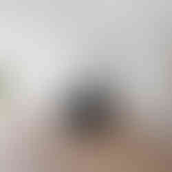 Open-concept kitchen and dining area with wood-look flooring, recessed ceiling lights, a black island with sink, white cabinets, white microwave and range, and a large white refrigerator. Sliding glass doors open to a wooden deck.