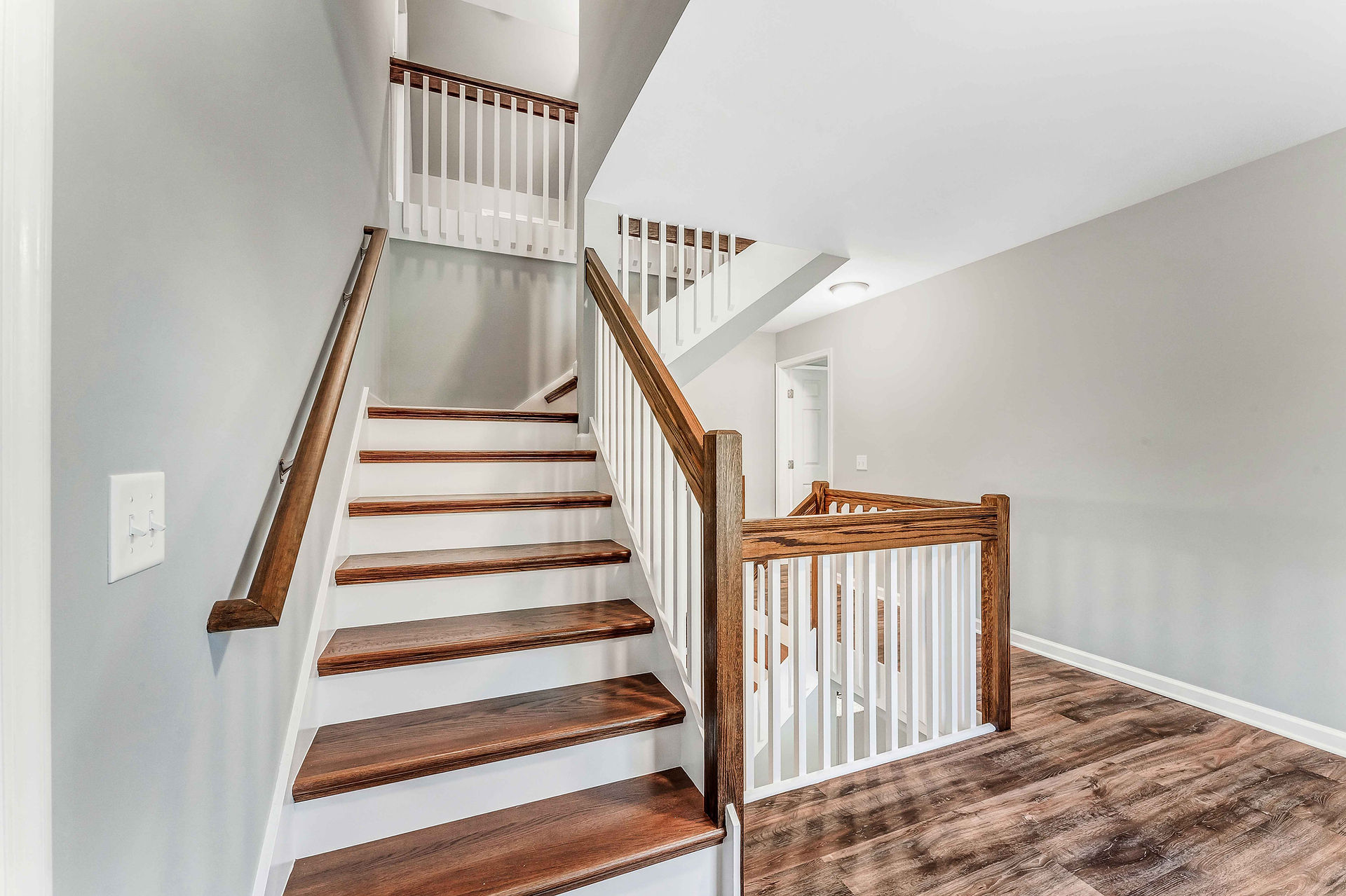 A close-up view of the stairs with wooden treads and white risers. A railing with wooden posts and w