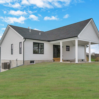 Exterior view of a two-story house in Northampton, PA. The house has white siding with black roofing, a covered porch with 6 white columns and wooden stairs leading to glass doors, and a spacious yard.