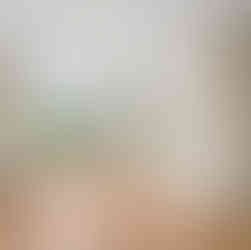 Interior view of an unfurnished room with beige walls, white trim, a white ceiling with a ceiling light, and warm brown wood-look flooring. There is a double window on the back wall and a single window on the rightside wall, bith providing natural light. An air vent and electrical outlet are seen on the back wall below the window.