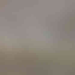 Commercial bar with a stone façade and granite countertop, highlighted by built-in accent lighting. Beer taps are mounted on the counter, and the space opens into a large hall with wood-style flooring, beige walls, and a drop ceiling with recessed lighting.