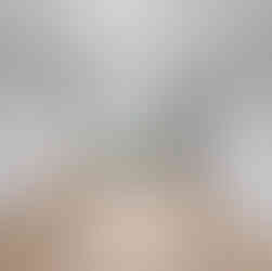 Unfurnished bedroom with light wood flooring, gray walls, and a white ceiling. The room has a large double window offering a view of a grassy landscape with trees. A white door leads to a hallway, and recessed baseboard trim lines the room. A ceiling-mounted light fixture provides light.