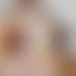 Interior top floor hallway landing space. The space has vaulted ceilings, white walls, exposed wood beam ceiling accents, and wood plank flooring. On the Left wall is an open dark wood door with light wood trim leading into another room. The next door is closed with a dark wood door with light wood trim. Next to the closed door is an open doorway with light wood trim leading into a bathroom.