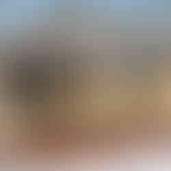 Rear exterior view of a tan two-story house in East Stroudsburg, PA with large gable windows, a screened-in porch, and an elevated wood deck on posts above a concrete foundation, with snow on the ground and leafless trees in the background.