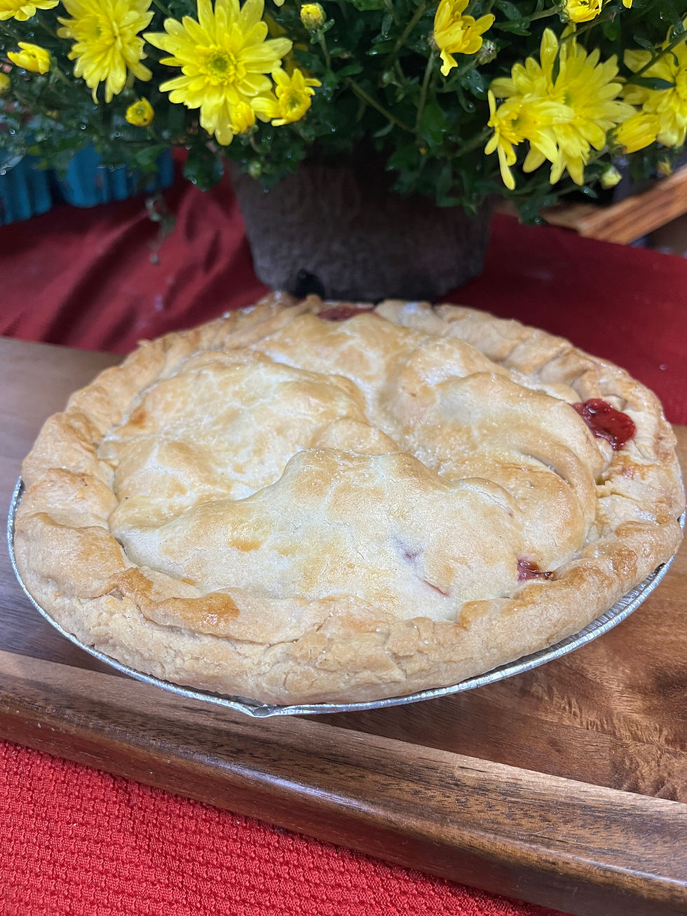 Freshly baked pie on a wooden board with flowers in background