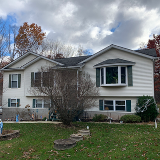 Exterior view of a two-story house in Effort, PA, with white siding, dark green shutters, and a small wooden staircase leading to a back door. The yard appears unlandscaped with visible dirt and patchy grass.