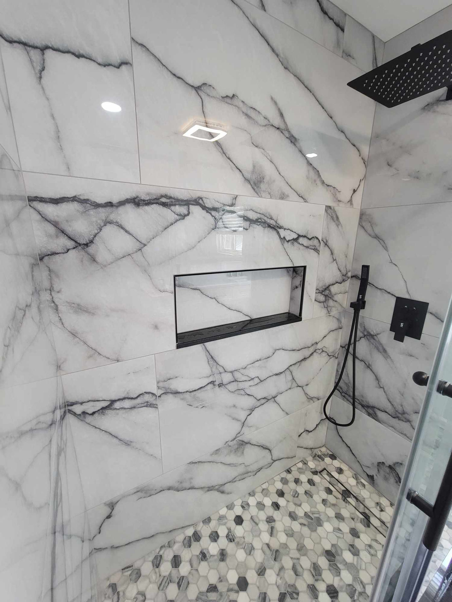 a shower with marble tiles and a black shower head
